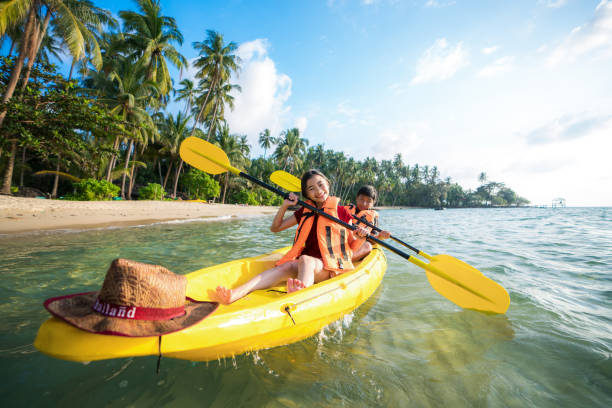 Asian kid to play Kayak on the beach on Koh Kood and Koh Mak, Koh Kood and Koh Mak is island on the sea of Thailand, This image can use for advanture, relax, travel, sport, travel and family concept