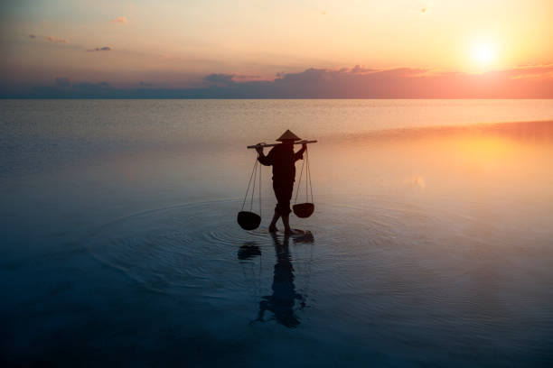 Farmer carrying baskets on the water.