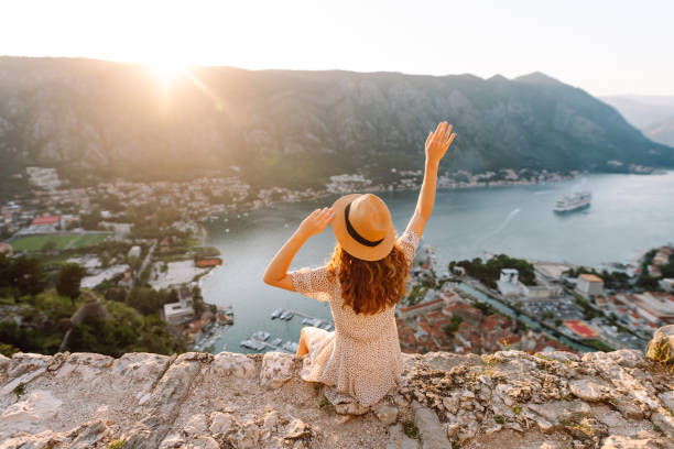 Back view of female tourist in a hat admires the landscape of the city. Lifestyle, vacation, tourism, nature, active life.