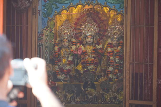 a man capturing photo of three idols of indian goddess in the temple