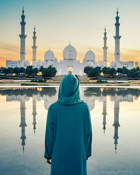 a tourist girl in a muslim dress Abaya pose travel photo while travels through the Great Mosque of Sheikh Zayed in Abu Dhabi
