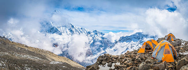 Mountaineering tents overlooked by the iconic pyramid peak of Machapuchare (6993m) high in the Himalayan mountain wilderness of the Annapurna Conservation Area, Nepal. ProPhoto RGB profile for maximum color fidelity and gamut.